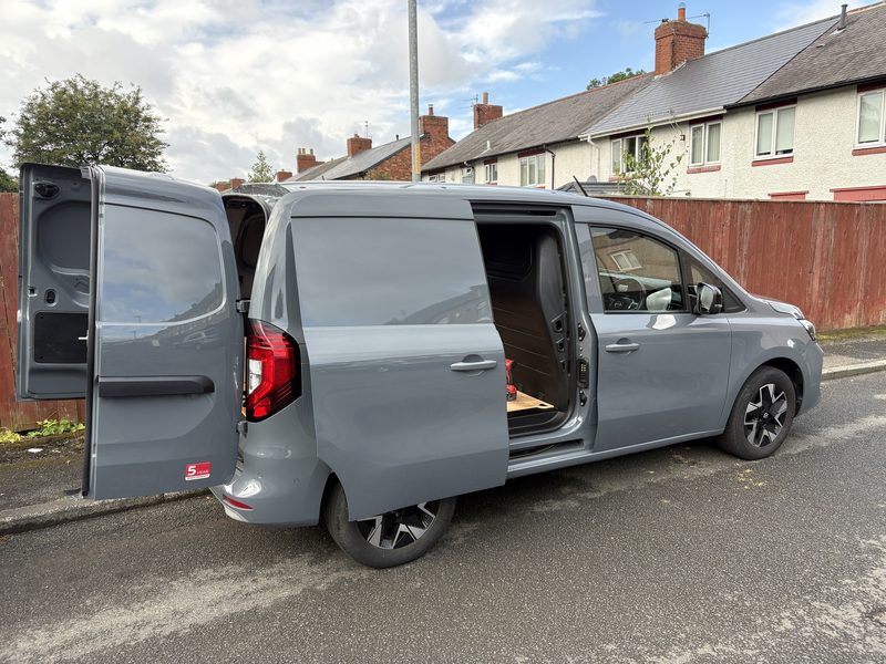 Van 001 build — side and rear doors open showing the plywood floor